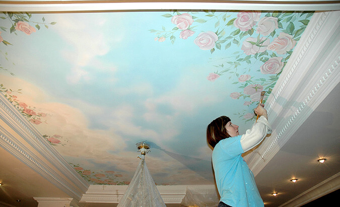 женщина разрисовывает натяжной потолок